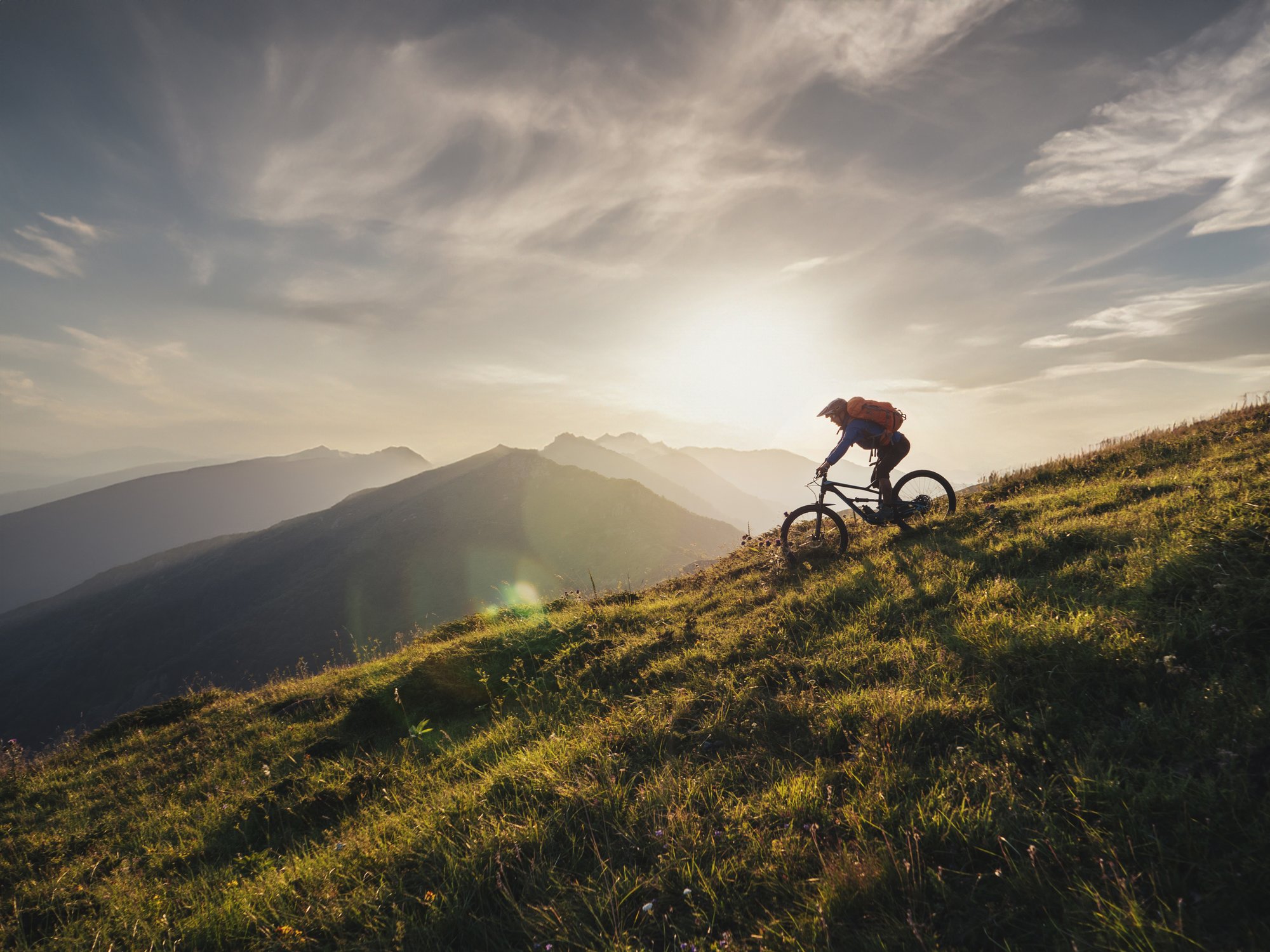 Header_Mountainbiker-riding-downhill-in-the-mountains-sunset-20231213-GLO-EN